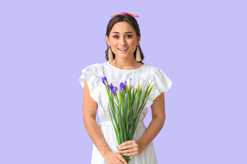 Young woman with creative makeup holding iris flowers on violet background. International Women's Day