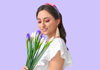 Woman with creative makeup looking at bouquet of iris flowers on violet background. International Women's Day