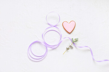 Figure 8 made of ribbon, tasty cookie and eucalyptus branch on light background. International Women's Day celebration