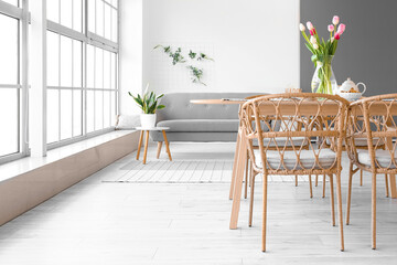 Vase with beautiful tulip flowers on dining table in room