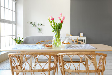 Vase with beautiful tulip flowers on dining table in room