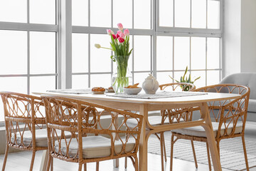 Vase with beautiful tulip flowers on dining table in room