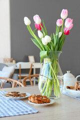 Vase with beautiful tulip flowers on dining table in room
