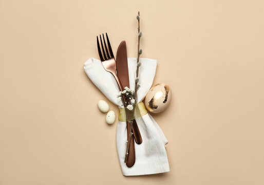 Stylish Easter cutlery on beige background