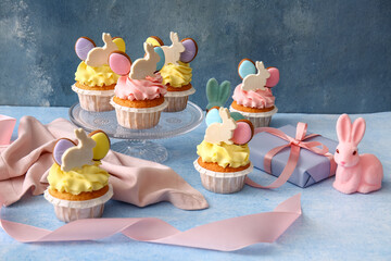 Tasty Easter cupcakes on blue background