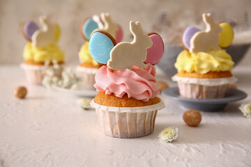 Tasty Easter cupcakes and eggs on light background, closeup
