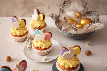 Tasty Easter cupcakes and eggs on light background