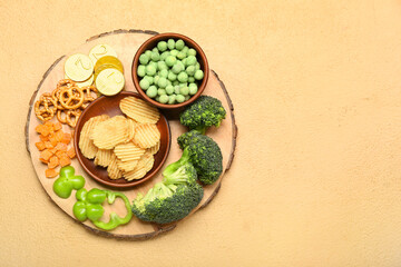 Fototapeta na wymiar Wooden board with different snacks for St. Patrick's Day celebration on beige background