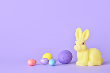 Cute Easter bunny and eggs on purple background