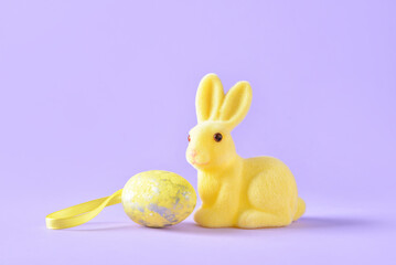 Easter bunny and painted egg on color background