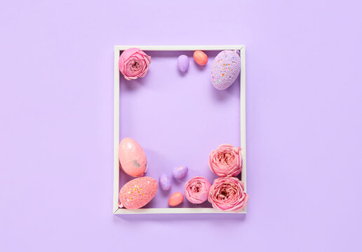 Beautiful composition with frame, Easter eggs and flowers on purple background