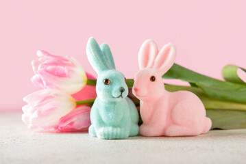 Easter bunnies and tulip flowers on color background