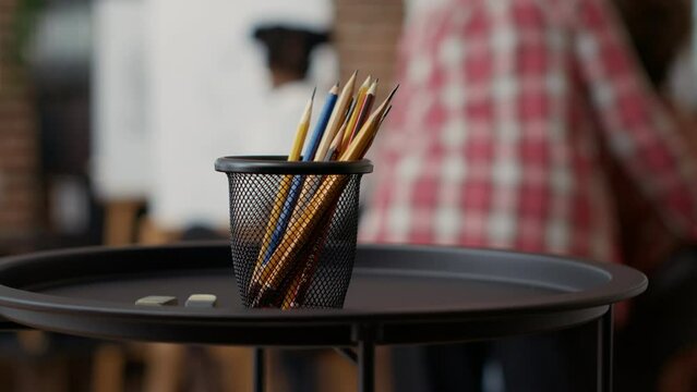 Colorful pencils and erasers on table used to draw artwork in creative workshop with students. Artistic instruments and tools to create modern sketch on canvas with easel for growth. Close up.