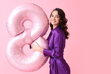 Smiling young woman with big balloon in shape of figure 8 on pink background. International Women's...