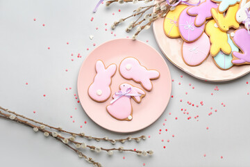 Plates with tasty Easter cookies and pussy willow branches on light background