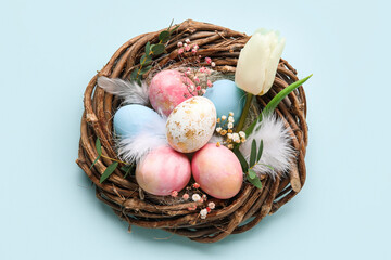 Nest with painted Easter eggs and flowers on blue background