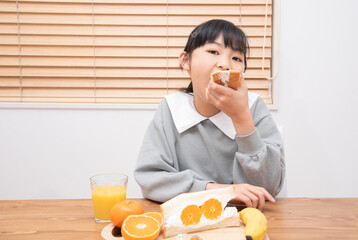 フルーツサンドを食べる小学生の女の子