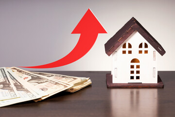 House price go up. Miniature wooden house, dollar money and up arrow.