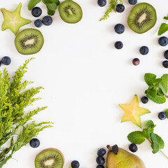 A top view of kiwis, blueberries, and star fruit on a white surface with space for text