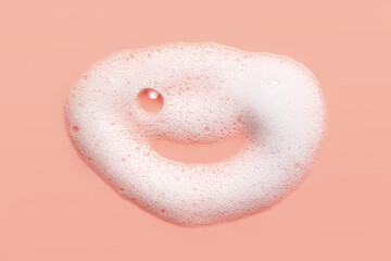 Soap cleanser foam texture. Shampoo bubbles funny face on pink background. Cosmetic foamy cleansing product swatch macro