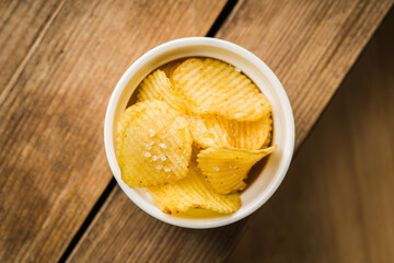 Salty grooved chips in white ceramic bowl on the rustic background. Selective focus. Shallow depth of field.