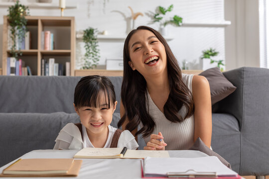 Happy asian young mother smile with daughter in living room at home. Asian young mother teaching small daughter to drawing reading and writing to develop her daughter skill. Home School Concept