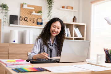 Asian young creative or graphic designer with curly hairstyle drawing or sketching on digital...