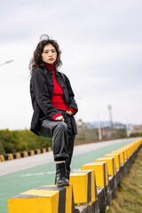 An Asian woman in a black leather coat outdoors