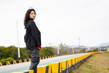 An Asian woman in a black leather coat outdoors