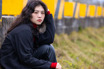 A woman dressed in black leather sat on a stone pier