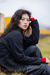 A woman dressed in black leather sat on a stone pier