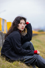 A woman dressed in black leather sat on a stone pier