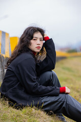 A woman dressed in black leather sat on a stone pier