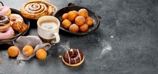 Table with various cookies, donuts, cakes and coffe cups