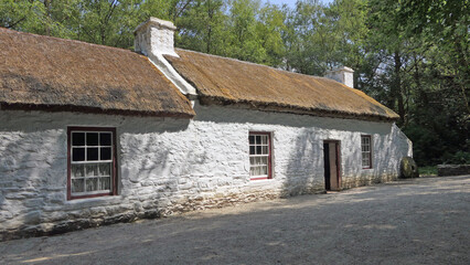 Fototapeta na wymiar Old Irish Traditional Whitewashed Cottage with thatched roof on a Farm in Ireland