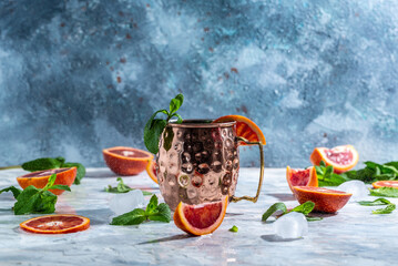 Moscow mule cocktail in copper cup with blood orange, ginger beer, vodka and mint. freeze motion splash