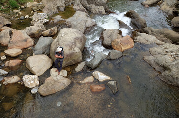 Backpack traveler leaning on a big rock in a creek in Sapa, Vietnam