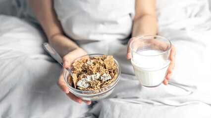 Close-up of cereal and a glass of milk in bed.