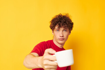 guy with red curly hair in a red T-shirt with a white cap in his hands isolated background unaltered