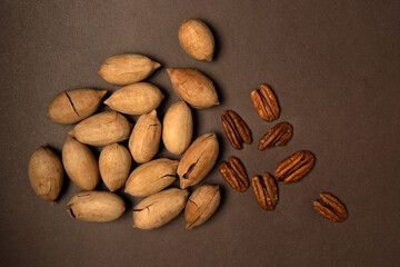 Several of pecan not purified and purified nuts on brown background