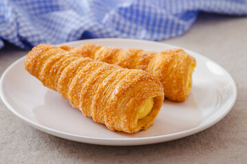 Puff pastry cream horn with vanilla cream on plate