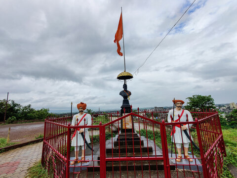 Stock photo of the great Maratha king Chatrapati Shivaji Maharaj statue, two warriors statue installed beside the kings statue, dark clouds on background. Picture captured at Kolhapur, Maharashtra.