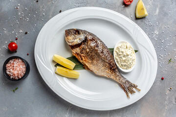 Delicious Grilled dorado fish with lemon and parsley. Whole Bbq sea bream baked. Dorado grill. Ketogenic, keto or paleo diet lunch, Healthy food trend. Top view