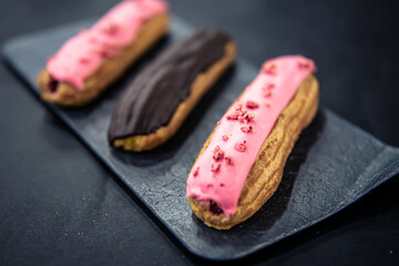 Chocolate and berry eclairs close-up on a black background.