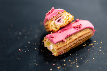 Close-up of a cut berry eclair on a black background.