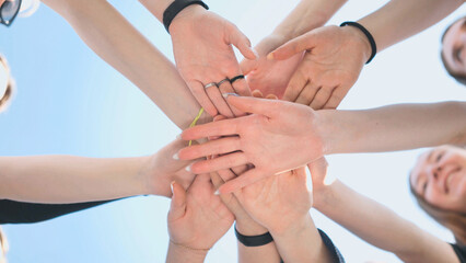 Cheerful girls join hands together as a sign of unity and joint successful work. Teamwork stacking hand concept.