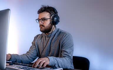 Male musician creates music using computer and keyboard, musician workplace.