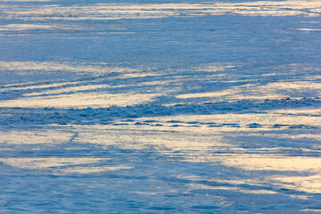 Snow on the lake in winter in the rays of sunset.