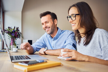 Obraz premium Small business partners discussing ideas in cafe using laptop