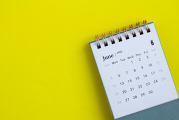 Desktop calendar for June 2022 on a yellow background.